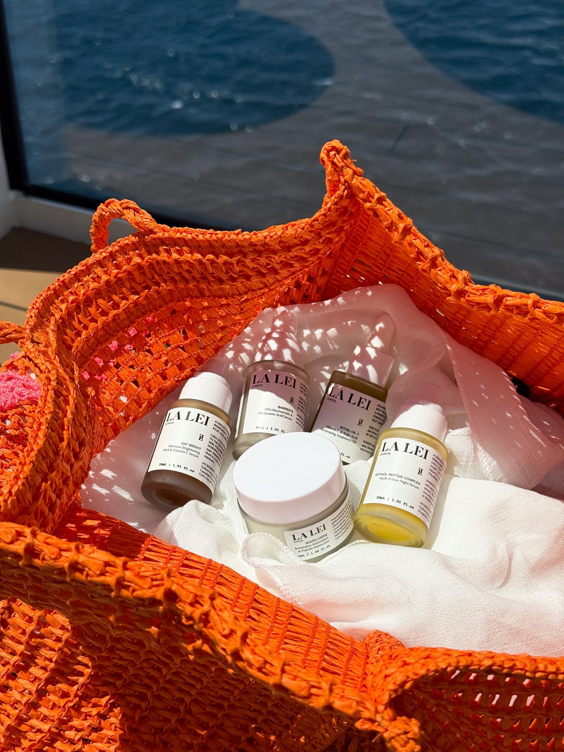 La Lei skincare edit styled in a woven bag, boat deck and ocean backdrop